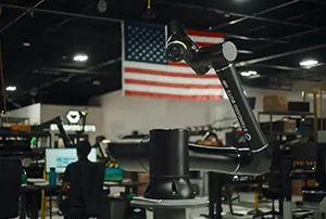 Illustration of AI-powered industrial robots operating on a modern factory floor, assembling products and supporting manufacturing processes. The image represents Standard Bots' $200 million Series C funding round and expansion of U.S. robot production, highlighting AI-native robotics, advanced automation, domestic manufacturing growth, and deployment across aerospace, automotive, defense, and industrial sectors.